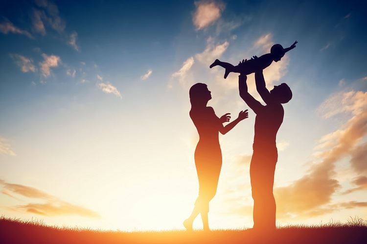 a silhouette of a man and woman holding a baby