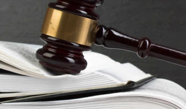 A lawyer's gavel rests on a stack of legal books, symbolizing justice and the legal profession.