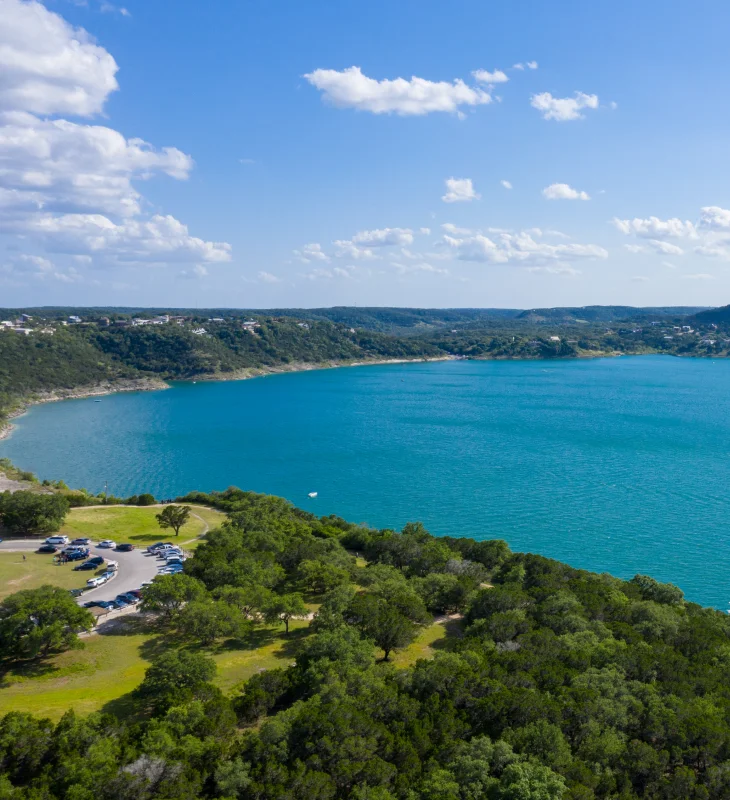 a lake with trees and a parking lot