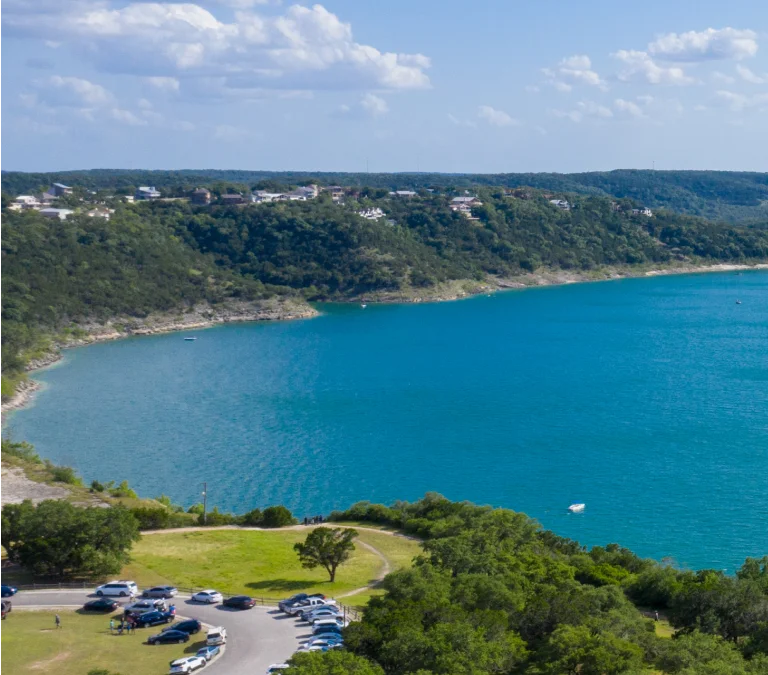 a blue water with trees and hills in the background