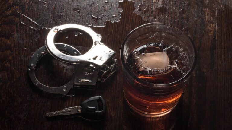 Rocks glass of whisky with handcuffs and keys
