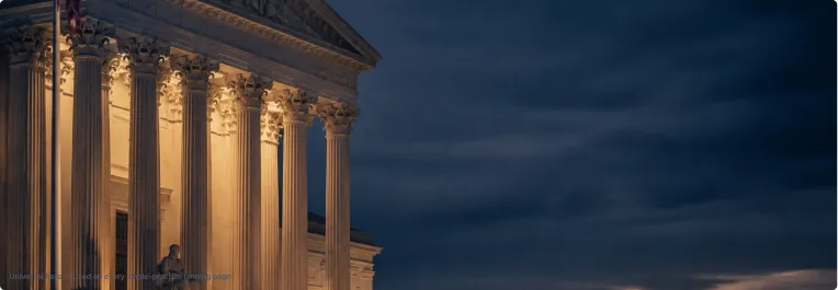 Illuminated classical building facade with Corinthian columns against twilight sky.